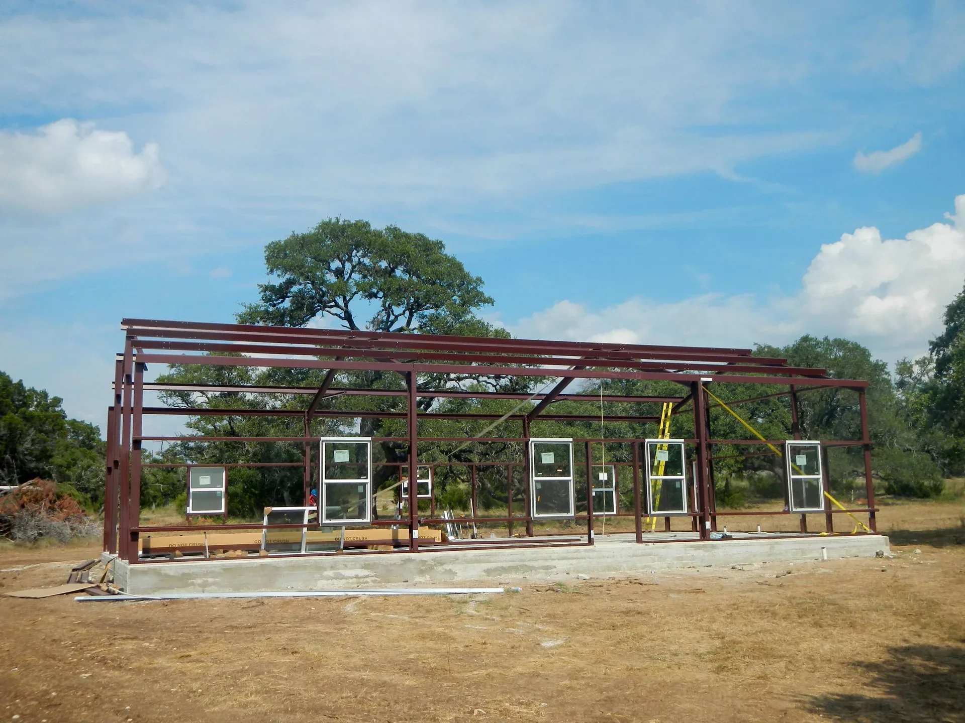Red-oxide primed rigid frame standing on a slab with window openings framed into the girts
